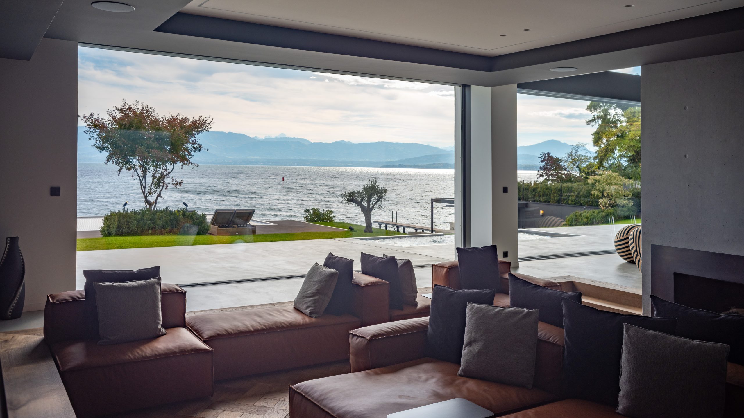 Baie vitrée minimaliste de grande dimension ouvrant sur une terrasse, système à cadre invisible